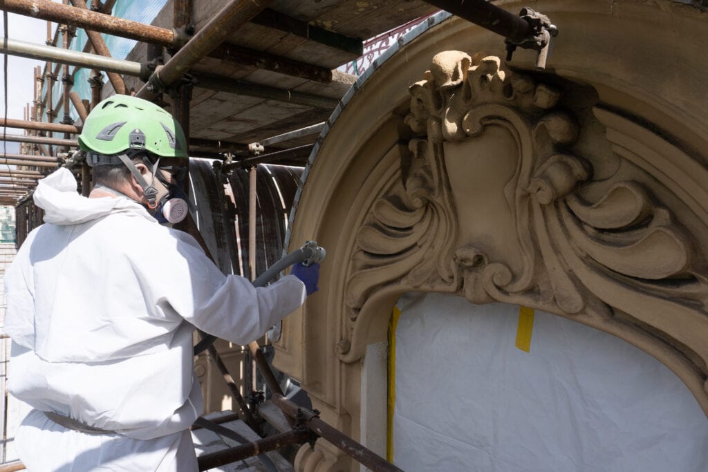Operai ripuliscono la facciata di un palazzo storico